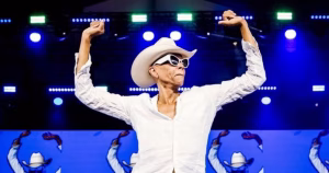 RuPaul, dressed in an all white cowboy outfit, strikes a pose on the stage of Drag Me To Cowboys 2026, the largest-ever drag show