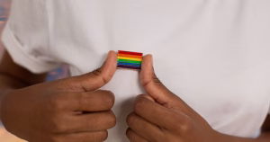 This article is about a new LGBTQ+ study in Ireland. The image shows the torso of someone in a white top, with a rainbow pin on their chest.