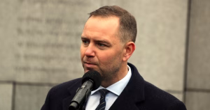 Polish President Karol Nawrocki, who recently vetoed a bill for same-sex couples' rights, speaking into a microphone while wearing a suit.