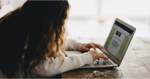 The image is of a woman with brown hair leaning over a laptop doing a survey