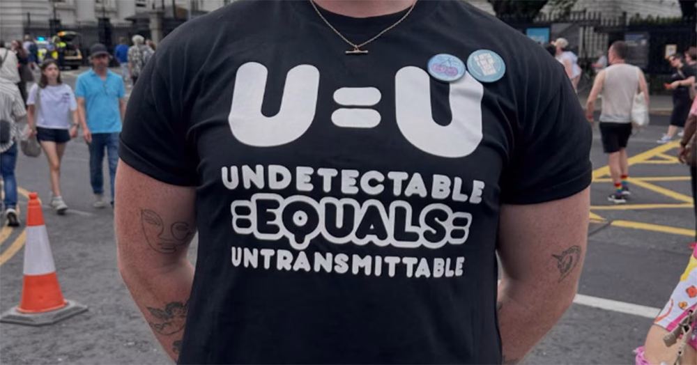 The torso of a person wearing a black HIV T-shirt with "U=U undetectable equals untransmittable" on it.
