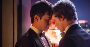 This article is about Heated Rivalry Season 2. In the photo, the two main characters are almost kissing while standing on a balcony.