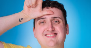 A promotional image for Conor Burke's new show Gleek of the Week. In the image, Conor smiles and holds his fingers in an L shape on his head.