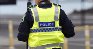 This article is about a PSNI officer dismissed over offensive messages. In the photo, the back of a police officer wearing a yellow vest.