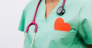 This article is about training for medical professionals on trans healthcare. The image shows the torso of a person in scrubs, with a stethoscope around their neck and a red paper heart in their chest pocket.