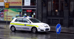 This article is about the murder of Alex Coughlan. In the photo, a Garda car driving on a street.