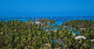 A high-angle image of the landscape of Fiji, showing green trees and blue waters.
