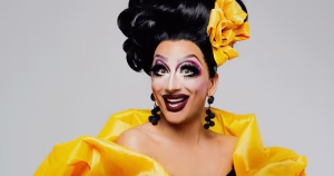 Drag performer Bianca del Rio posing for a picture in full drag with a bright yellow dress.
