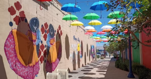An image from a street in Palm Springs with a painted wall, multicoloured umbrellas and blue skies.