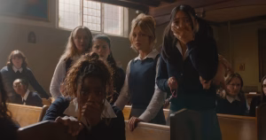 A screenshot from the trailer of The Body showing a group of Catholic schoolgirls looking in shock at the camera.